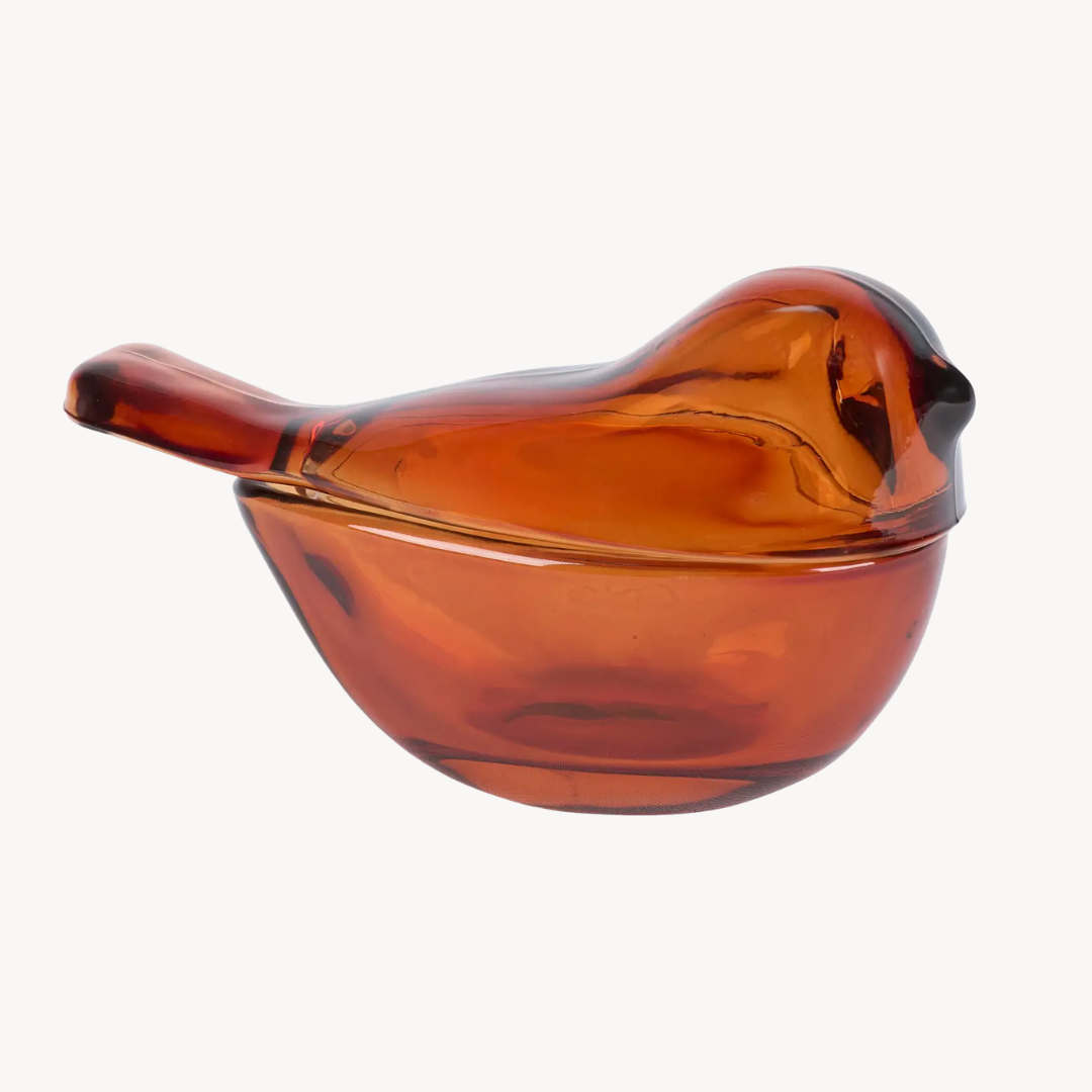 An amber glass bird-shaped container with a matching lid, shown against a plain light gray background.