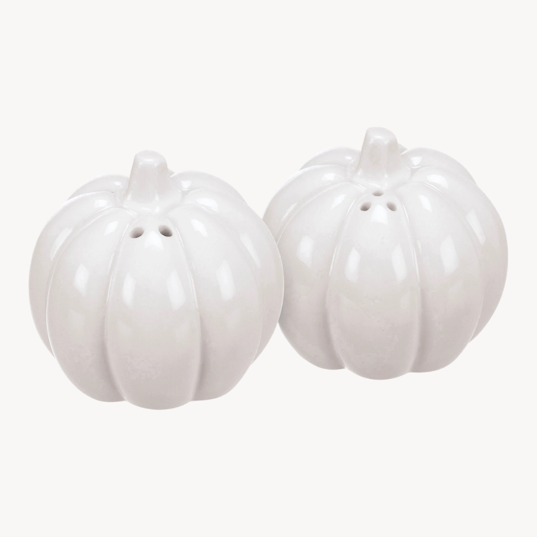 Two glossy white ceramic pumpkins with small top holes, likely salt and pepper shakers, shown on a plain light background.