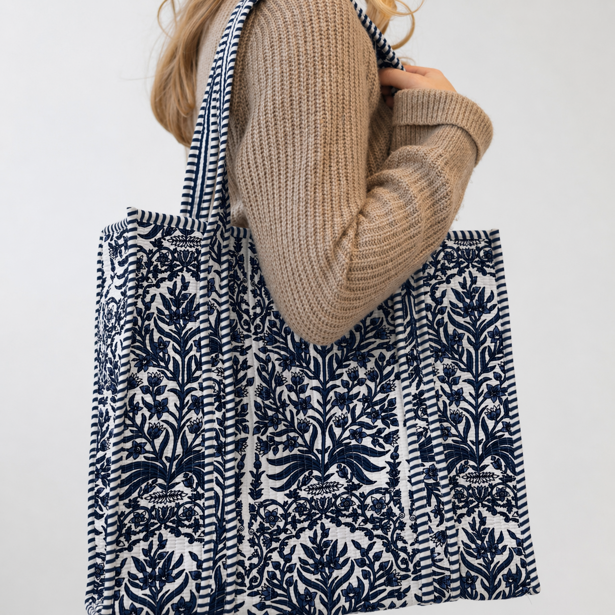 Person holding a blue patterned tote bag against a white background