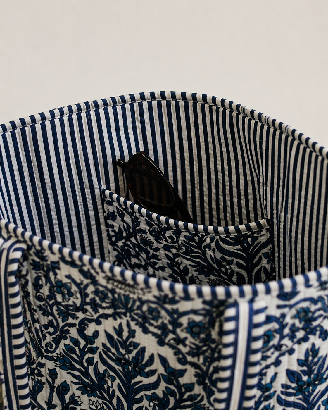 Close-up of a striped fabric with sunglasses inside, on a light gray background